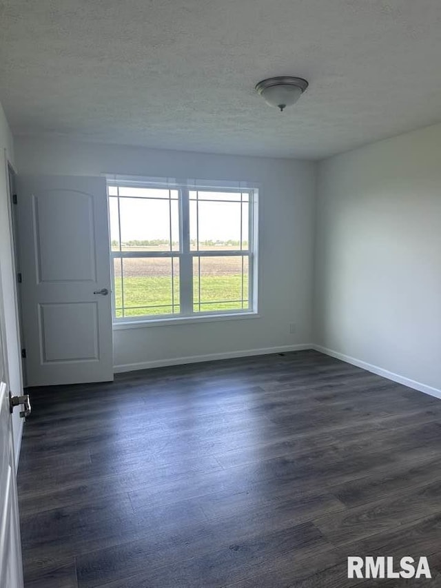 spare room with a textured ceiling, baseboards, and dark wood-style floors