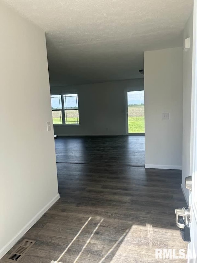 hallway with baseboards, visible vents, and dark wood-type flooring