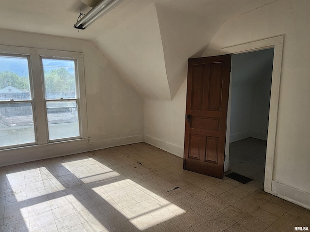 additional living space with baseboards and vaulted ceiling