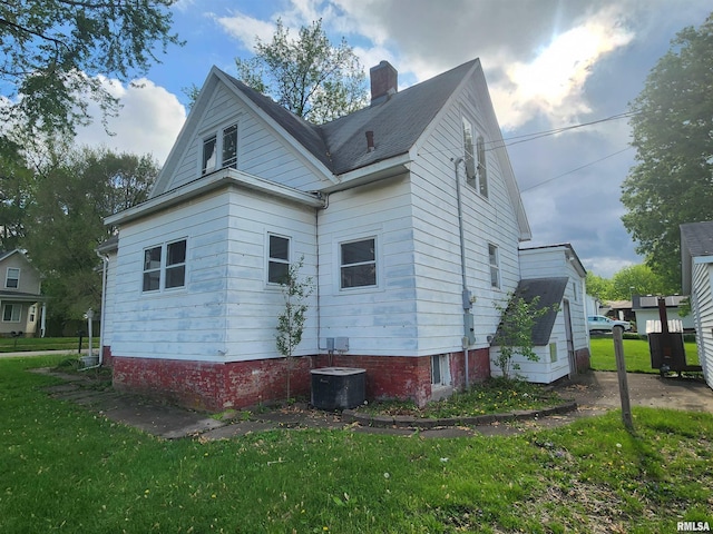back of house featuring a lawn, a chimney, and cooling unit