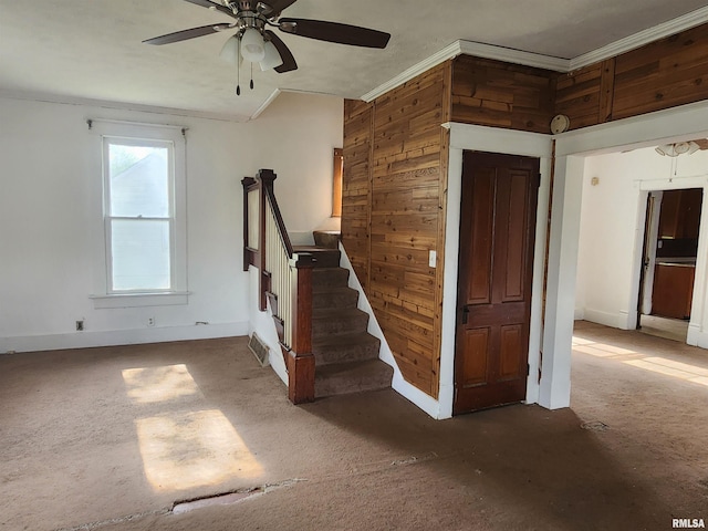interior space featuring carpet floors, ceiling fan, crown molding, and baseboards