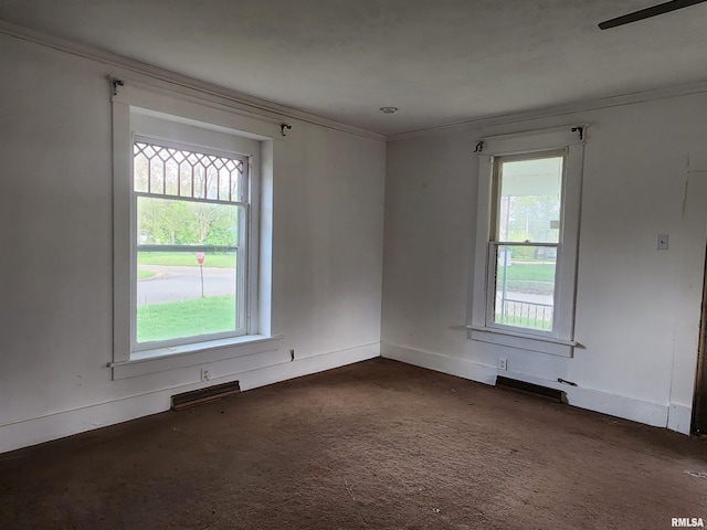 spare room with crown molding, baseboards, and dark colored carpet