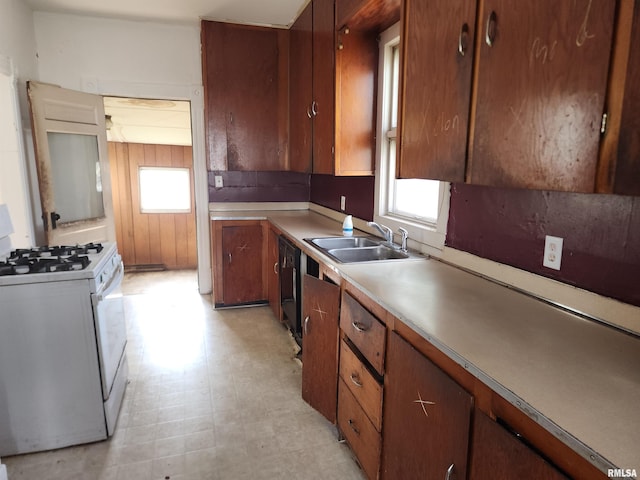 kitchen with a sink, light floors, light countertops, white gas range oven, and dishwasher
