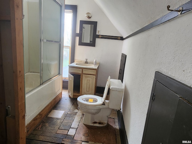 full bathroom with shower / bath combination with glass door, a textured wall, vanity, toilet, and vaulted ceiling