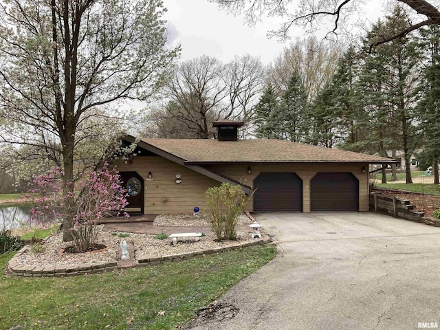 single story home with concrete driveway, a shingled roof, and an attached garage