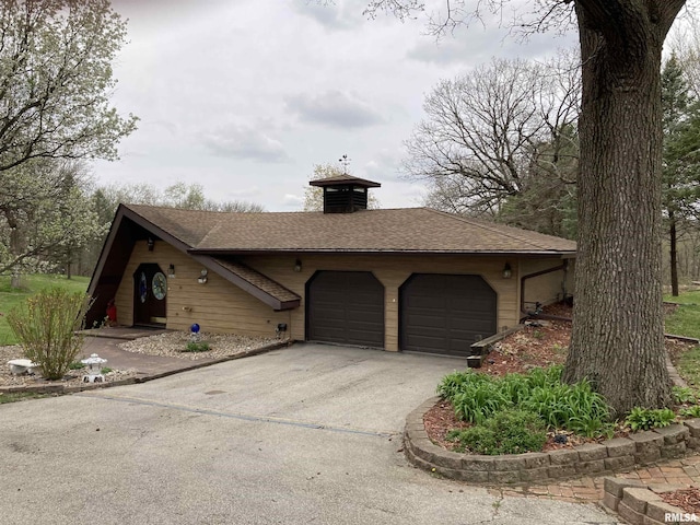 view of front of house featuring a shingled roof, driveway, and a garage