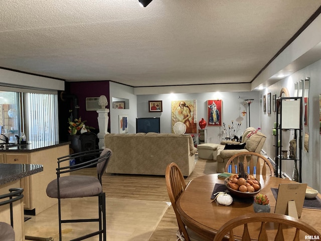 dining space with crown molding, light wood-type flooring, an AC wall unit, and a textured ceiling