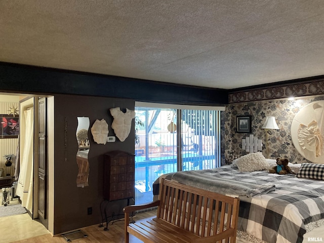 bedroom featuring light wood finished floors, access to outside, and a textured ceiling