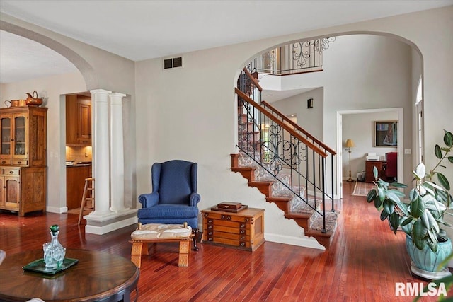 living area featuring baseboards, visible vents, stairs, hardwood / wood-style flooring, and arched walkways