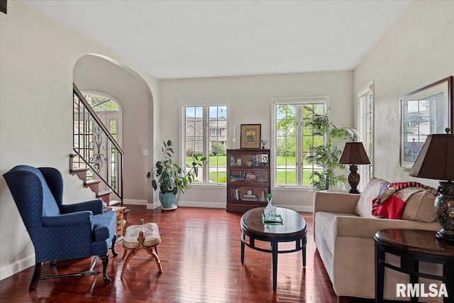 living room with stairs, wood finished floors, visible vents, arched walkways, and baseboards