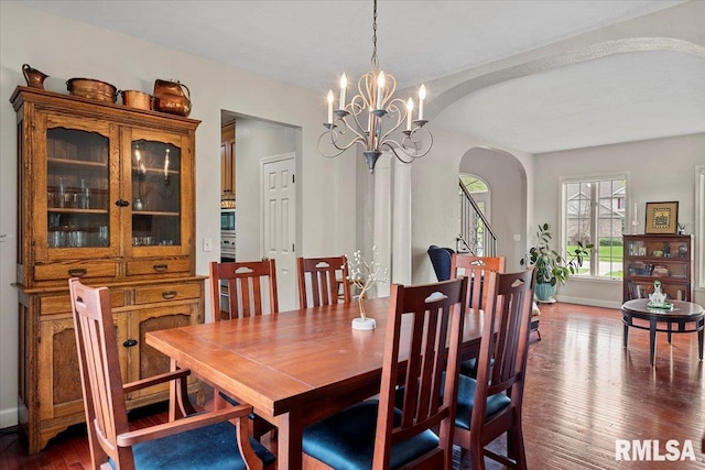 dining room with arched walkways, a notable chandelier, dark wood-style floors, and baseboards
