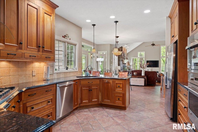 kitchen featuring brown cabinetry, open floor plan, appliances with stainless steel finishes, and a sink