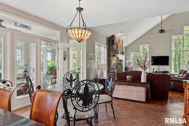 dining area featuring vaulted ceiling, dark tile patterned floors, and a ceiling fan