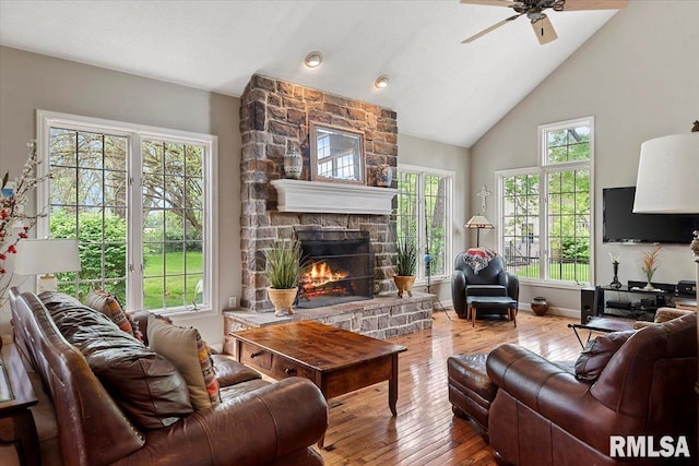 living room featuring ceiling fan, a wealth of natural light, a fireplace, and wood-type flooring