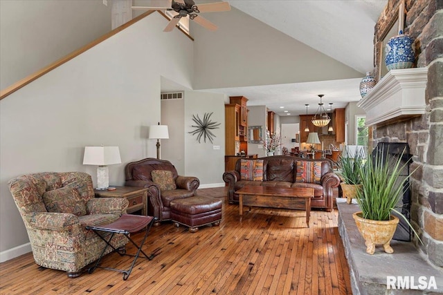 living room featuring a ceiling fan, baseboards, wood-type flooring, visible vents, and high vaulted ceiling