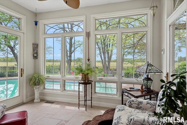 sunroom with baseboards, visible vents, and plenty of natural light