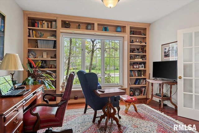 office featuring built in shelves, a wealth of natural light, and wood finished floors