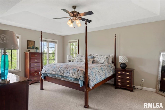 carpeted bedroom featuring baseboards, a raised ceiling, and ceiling fan