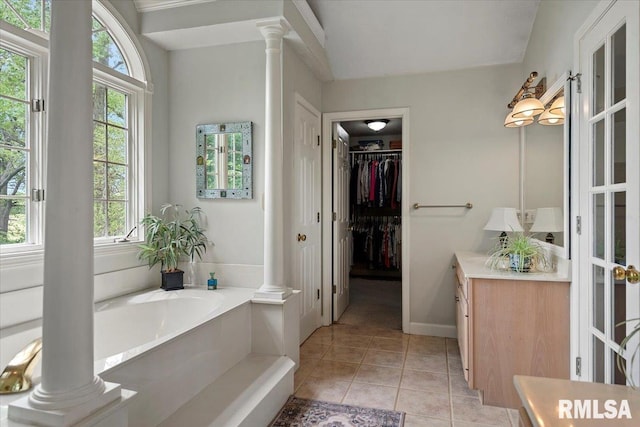 full bathroom with a wealth of natural light, tile patterned flooring, vanity, and ornate columns
