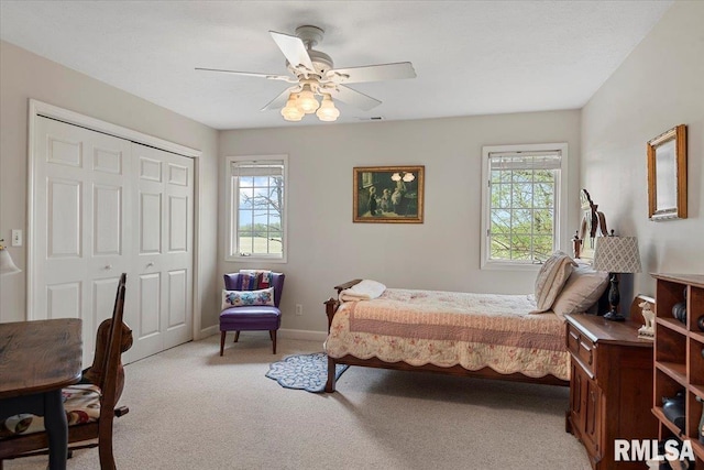 bedroom with ceiling fan, light carpet, a closet, and baseboards