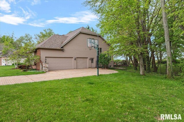 view of side of property with an attached garage, fence, roof with shingles, a yard, and driveway