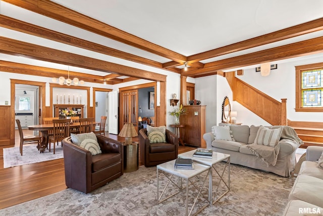 living room featuring an inviting chandelier, wood finished floors, beamed ceiling, and stairs