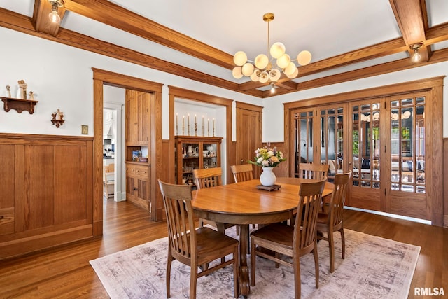 dining space featuring coffered ceiling, a wainscoted wall, beamed ceiling, and an inviting chandelier