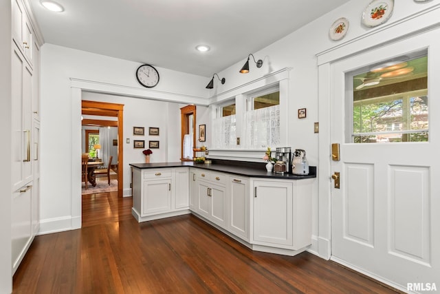kitchen featuring dark wood-style flooring, dark countertops, a peninsula, and plenty of natural light