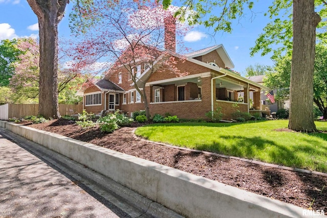 view of front of property featuring covered porch, fence, brick siding, a front lawn, and a chimney