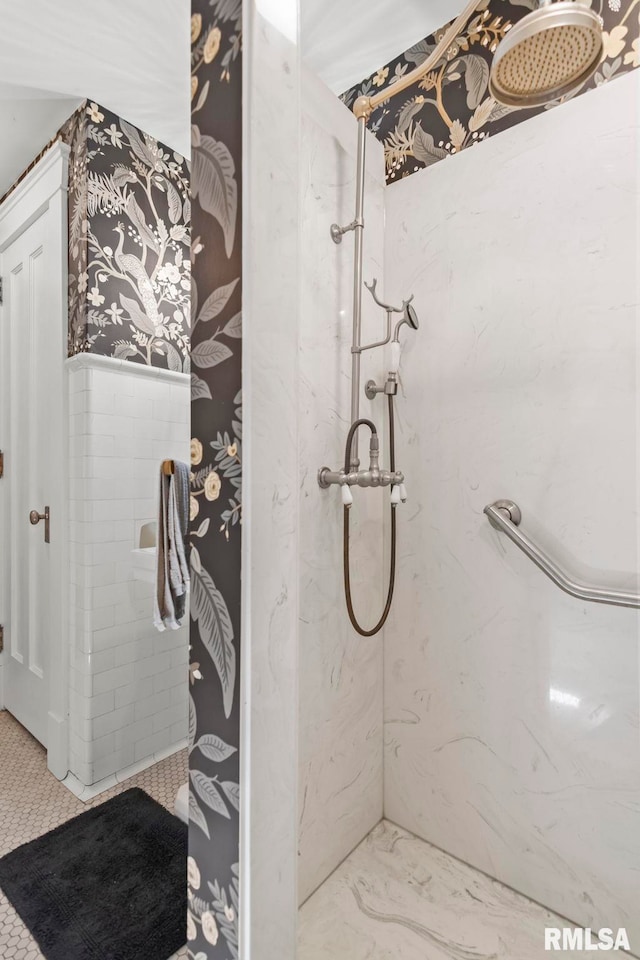 bathroom featuring a marble finish shower and wallpapered walls