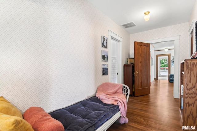 bedroom featuring visible vents, wallpapered walls, and wood finished floors