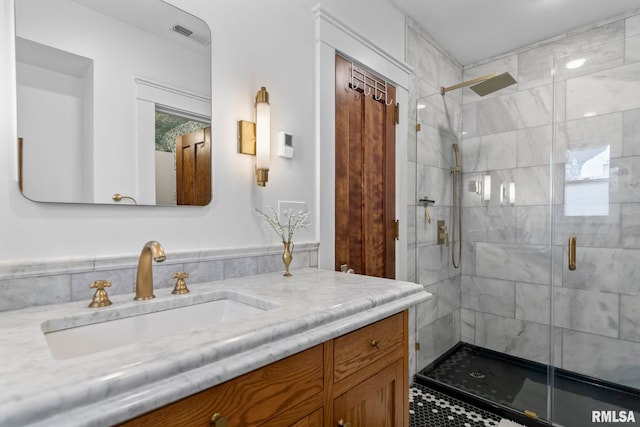 bathroom with a shower stall, vanity, and visible vents