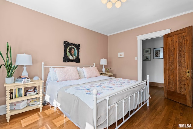bedroom with crown molding, baseboards, and wood finished floors