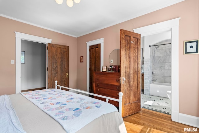bedroom with ensuite bathroom, wood finished floors, and ornamental molding