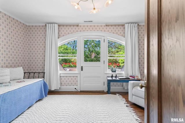 bedroom featuring wallpapered walls, wood finished floors, visible vents, and multiple windows