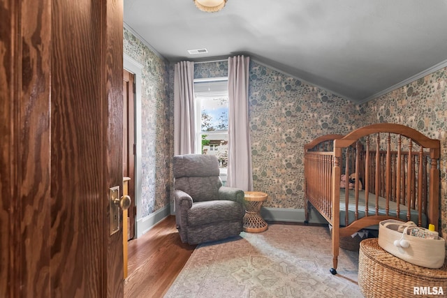 bedroom with wallpapered walls, vaulted ceiling, wood finished floors, and baseboards