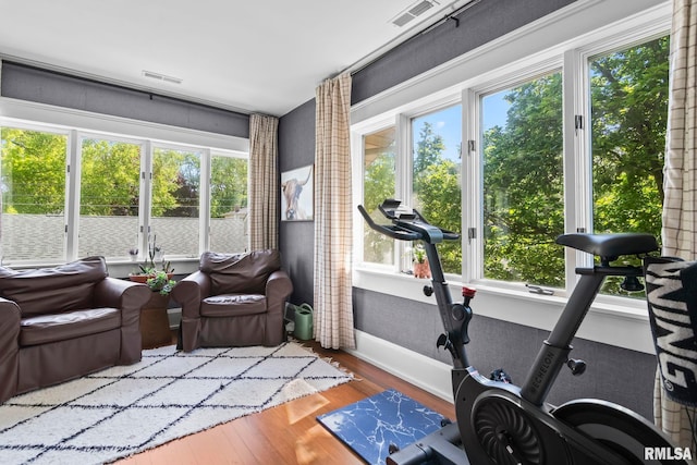 workout area featuring visible vents, wood finished floors, and baseboards