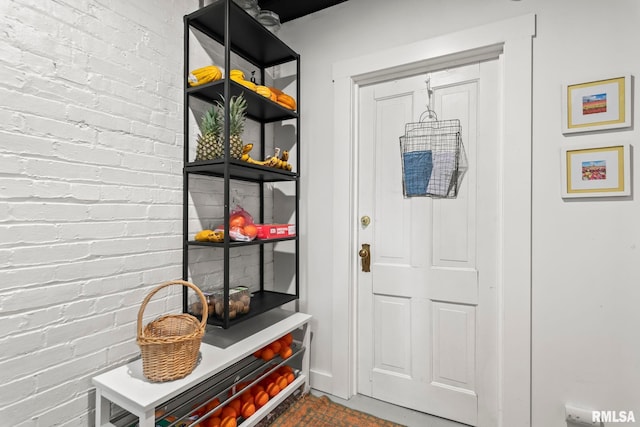 mudroom featuring brick wall