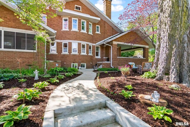 view of front of house featuring a chimney and brick siding