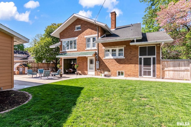 back of property with fence, brick siding, a patio, a chimney, and a lawn