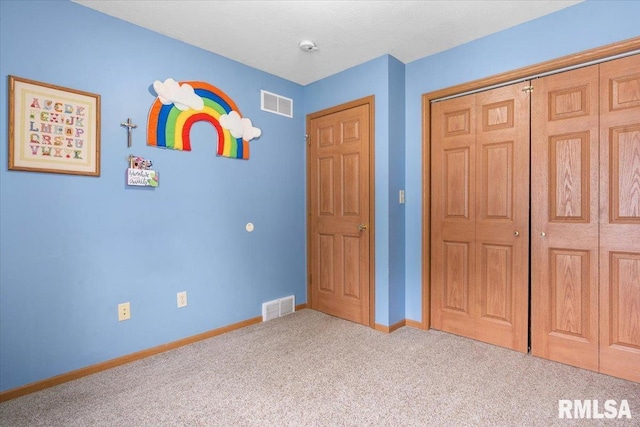 unfurnished bedroom with carpet floors, baseboards, visible vents, and a closet