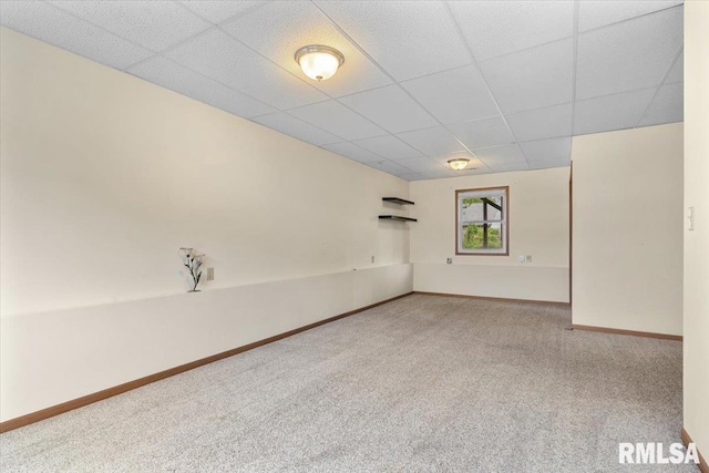 carpeted empty room featuring a paneled ceiling and baseboards