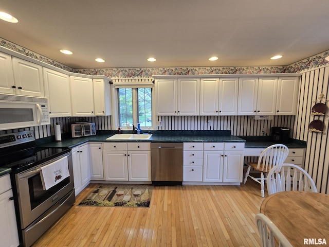 2704 Kings Pointe NE Unit 2704, Quincy, IL 62305 - kitchen featuring light wood finished floors, a sink, dark countertops, stainless steel appliances, and white cabinetry