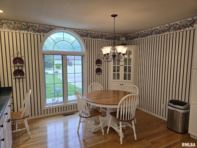 2704 Kings Pointe NE Unit 2704, Quincy, IL 62305 - dining room with light wood-style flooring, wallpapered walls, a wealth of natural light, an inviting chandelier, and visible vents