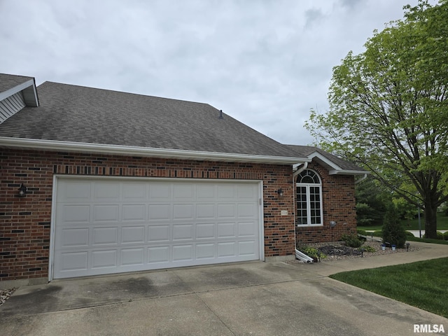 2704 Kings Pointe NE Unit 2704, Quincy, IL 62305 - view of side of home with roof with shingles, concrete driveway, an attached garage, and brick siding