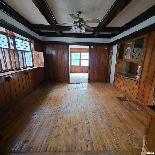 207 W Main St, Knoxville, IL 61448 - spare room featuring a ceiling fan, light wood-type flooring, visible vents, wooden walls, and beam ceiling