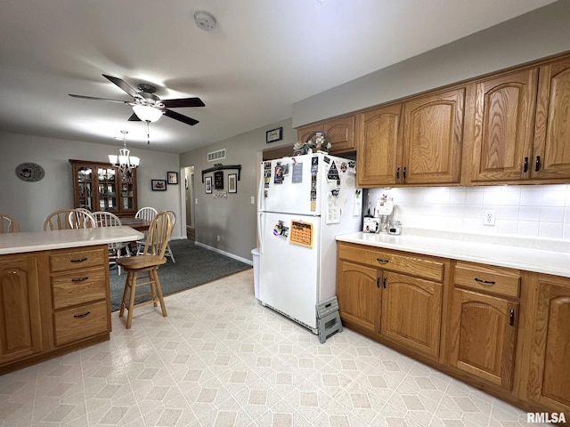 kitchen featuring freestanding refrigerator, brown cabinets, and ceiling fan with notable chandelier