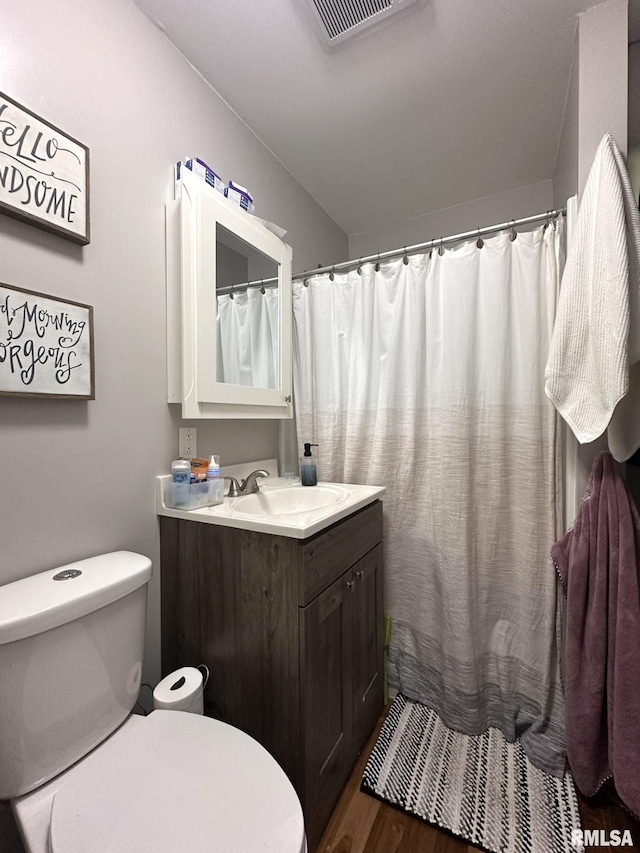bathroom featuring toilet, visible vents, wood finished floors, and vanity