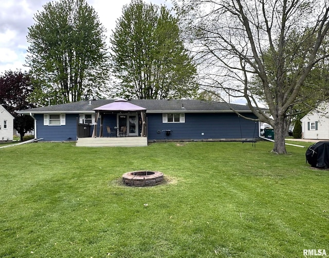 rear view of property featuring a yard, a sunroom, and a fire pit