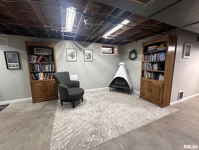sitting room with concrete flooring, baseboards, and visible vents